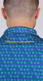 Close-up back view of a person wearing a blue 4-leaves Clover patterned collared shirt with green clover motifs and yellow 'Mulligan Hooligan' script on the collar.