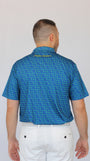 A man viewed from behind wearing a blue short-sleeve Clover patterned golf shirt and white pants against a plain light gray background.