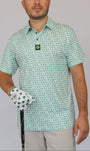 A man wearing a short-sleeve polo shirt with a green and white shamrock pattern, holding a golf club and wearing a matching white golf glove with green shamrocks. The background is a solid light gray.