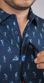 Close-up of a man wearing a navy blue golfing skeletons patterned shirt and holding his sunglasses on a placket custom loop. 