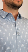 A close-up of a man wearing a light gray, silver polo shirt with a white all-over golf-themed skeletons playing golf graphic print, featuring golf clubs and players.