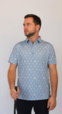 A man wearing a light gray short-sleeve polo shirt with white goofing skeletons pattern, standing against a plain light gray background.