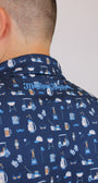 Close-up of a person wearing a navy blue Golf Dad Polo with a repeating pattern of golf clubs and a script of 'Mulligan Hooligan' logo.