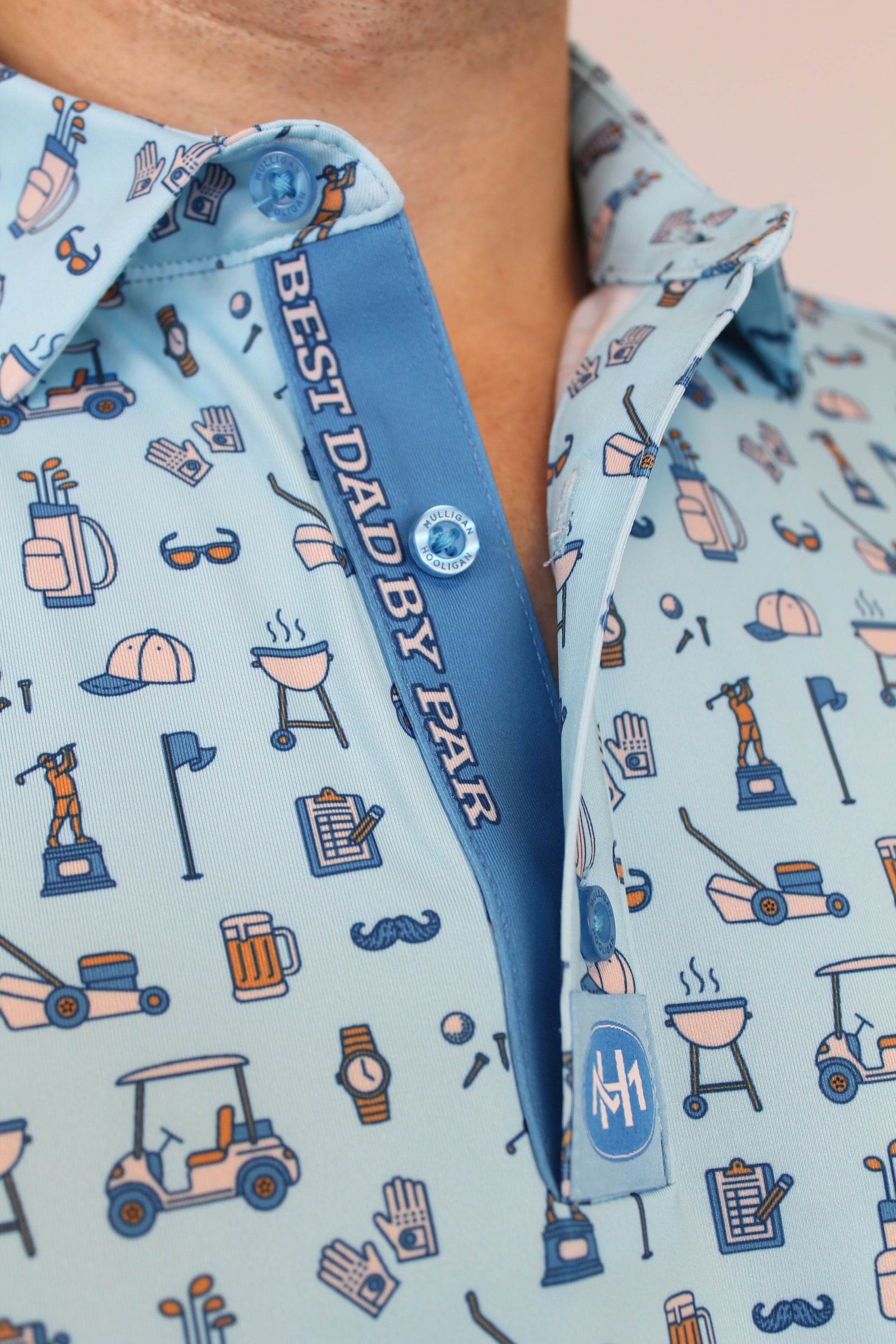 Close-up of a light blue patterned button-up shirt with a blue placket reading 'BEST DAD BY PAR' and a small circular logo patch.