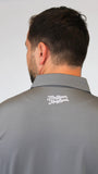 Back view of a man wearing a gray collared polo shirt with 'Mulligan Hooligan' 3D  in white script on the upper neck, against a plain light gray background.