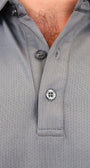 Close-up of a gray short-sleeve polo shirt with a micro-perforated text saying "Mulligan Hooligan', featuring a 3-button placket.