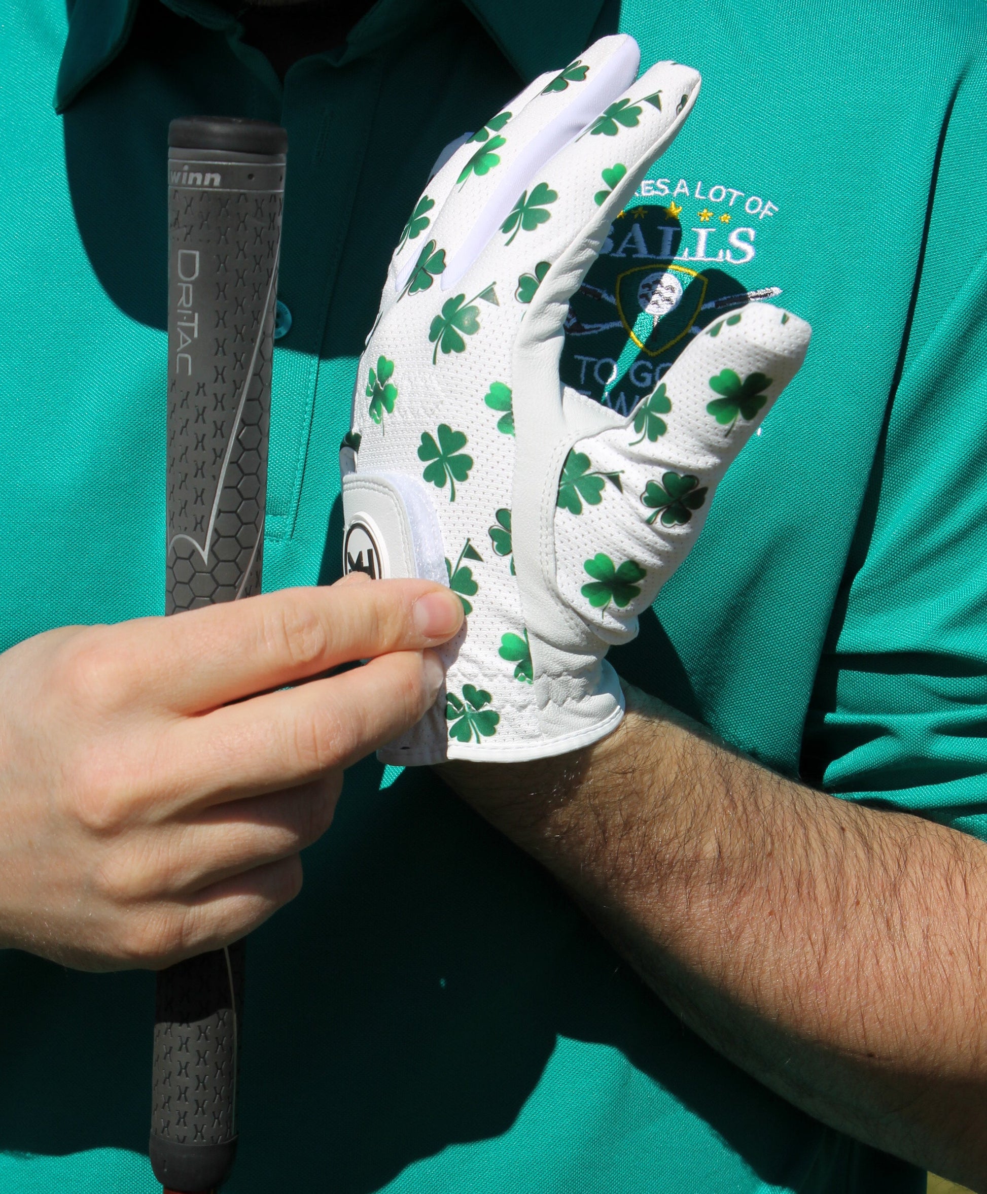 'Clover Luck' golf glove with shamrock pattern and little golf flags on a person hand close-up 
