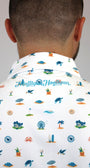 Back view of a man wearing a white collared shirt with a colorful 'Mulligan Hooligan' golf-themed print, featuring blue, green, and orange illustrations of golf course elements.