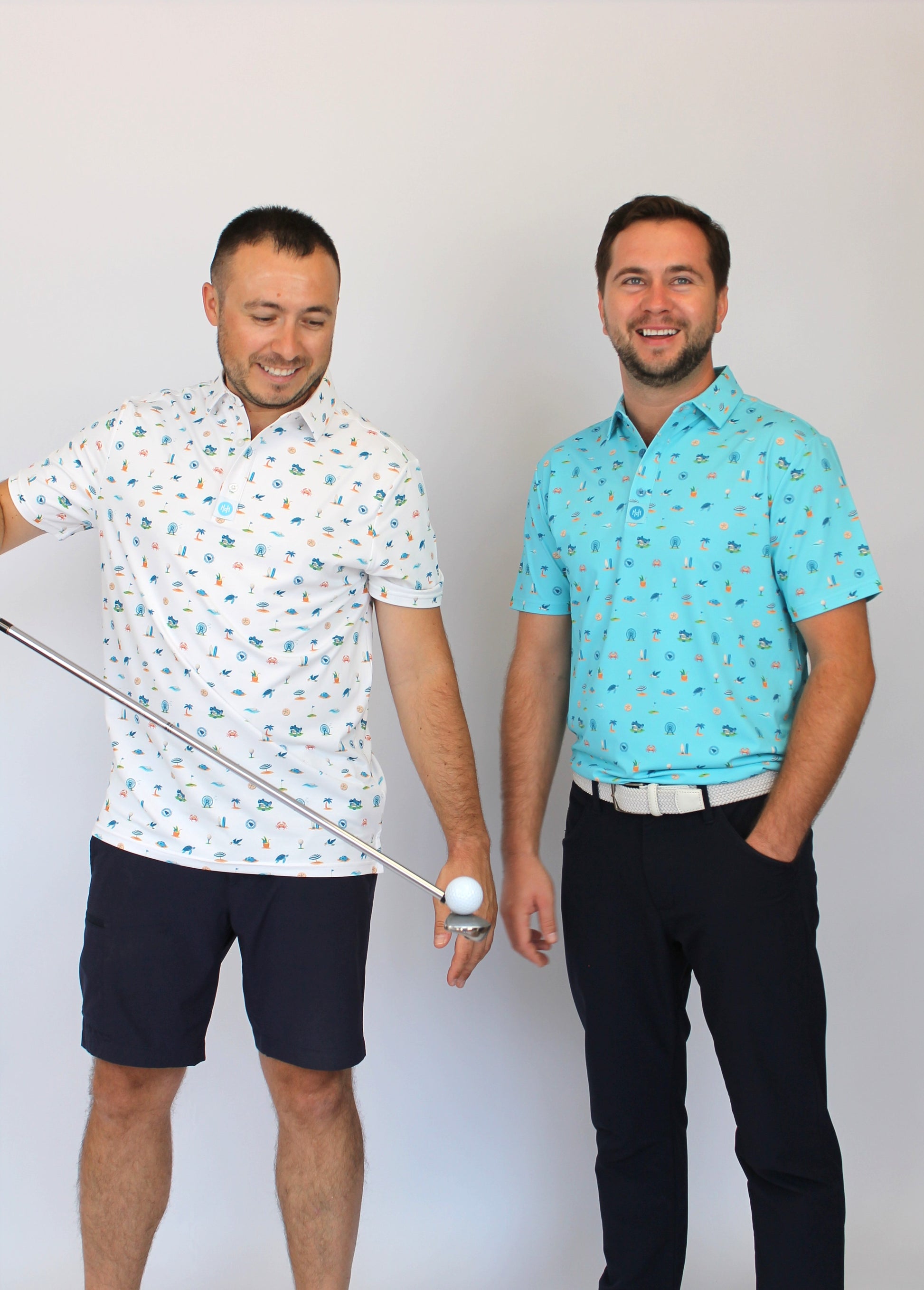 Two men standing side by side wearing matching beach-theme & golf-theme patterned short-sleeve button-up shirts, one in white and the other in light blue, with dark pants, against a plain light background.
