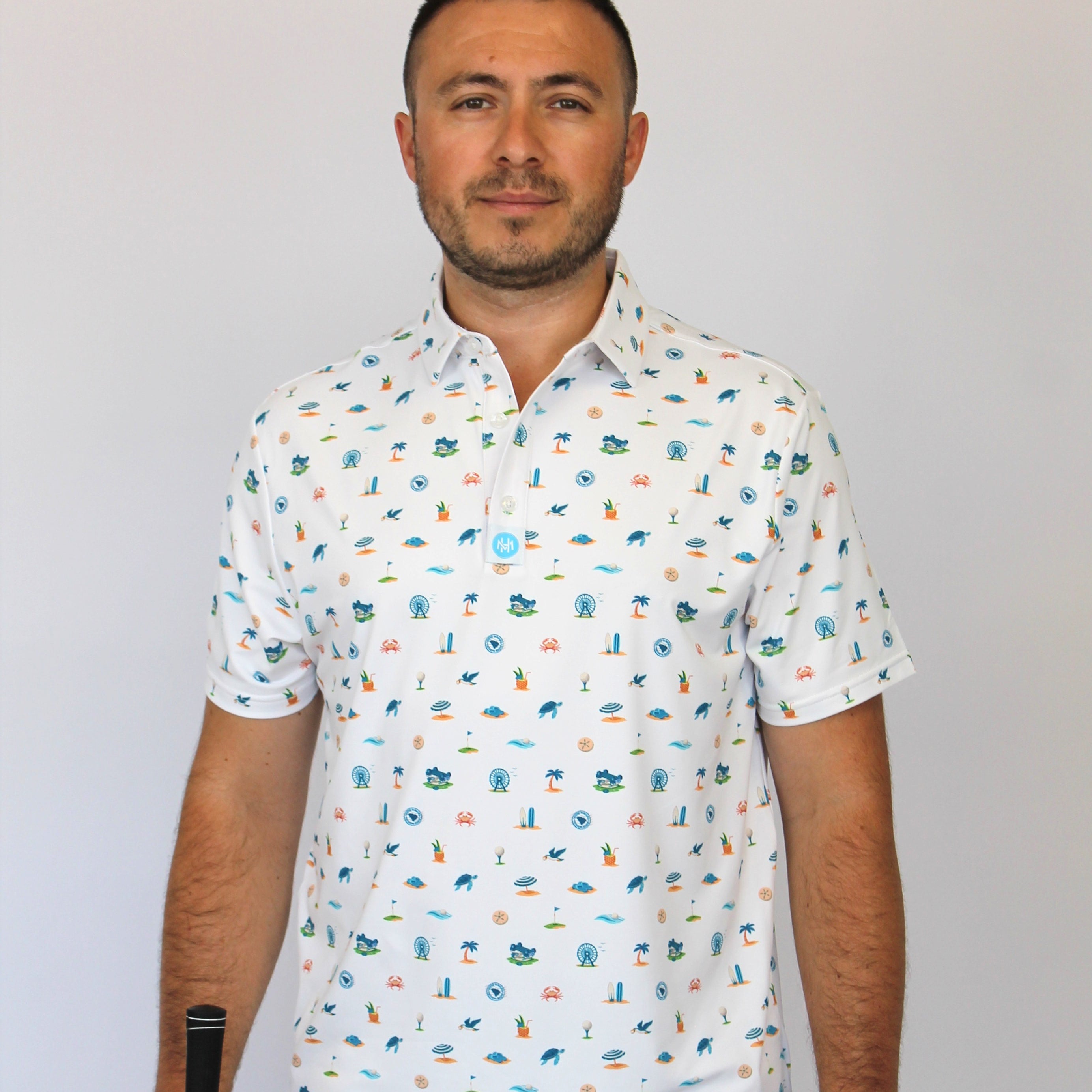 A man wearing a white short-sleeve button-up shirt with a colorful golf-themed and beach-theme, Myrtle Beach, SC pattern, holding a golf club and ball.