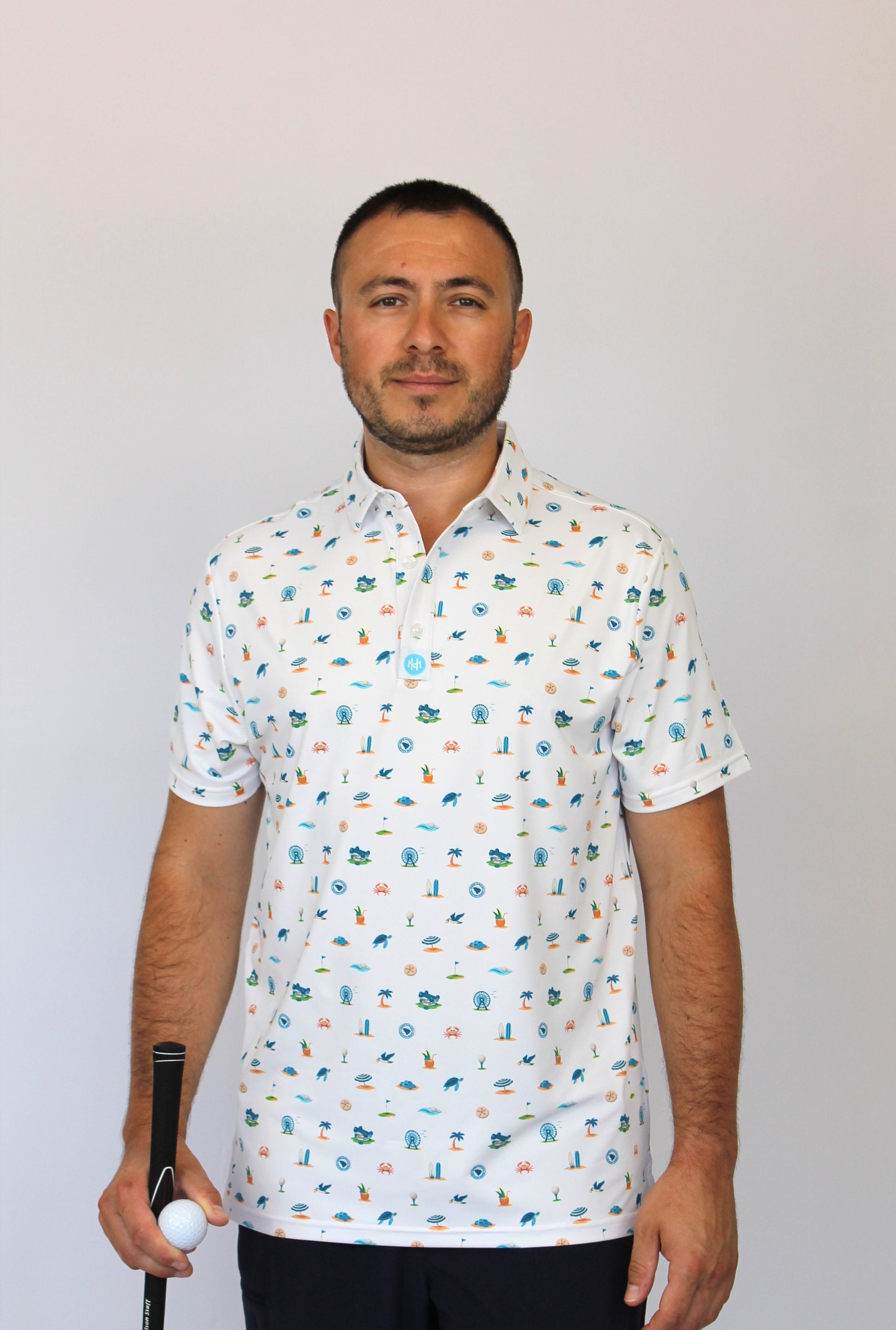 A man wearing a white short-sleeve button-up shirt with a colorful golf-themed and beach-theme, Myrtle Beach, SC pattern, holding a golf club and ball.