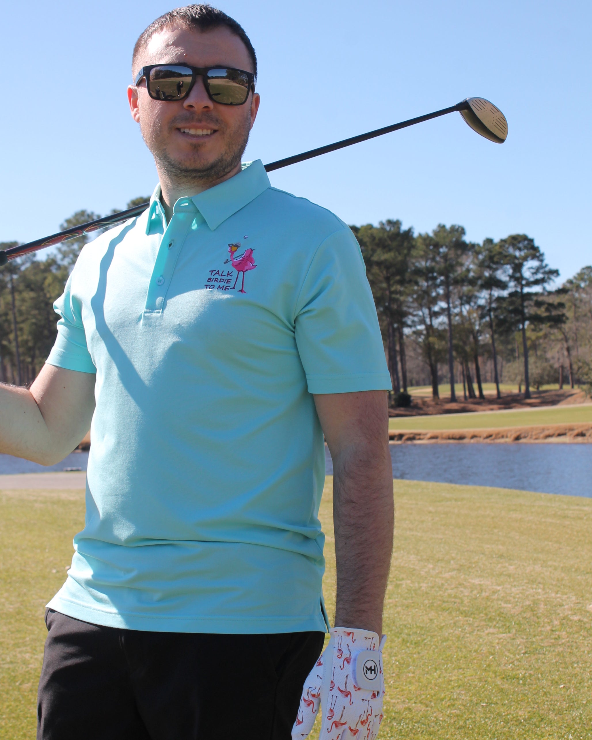 Person holding a golf club on a golf course with trees in the background