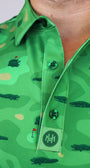 Close-up of a green collared button-up shirt with an alligator and golf course pattern, featuring green buttons and a branded 'Mulligan Hooligan' Custom Engrave.