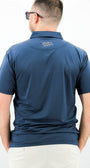Man wearing a blue polo shirt with a brand logo on the back against a white background