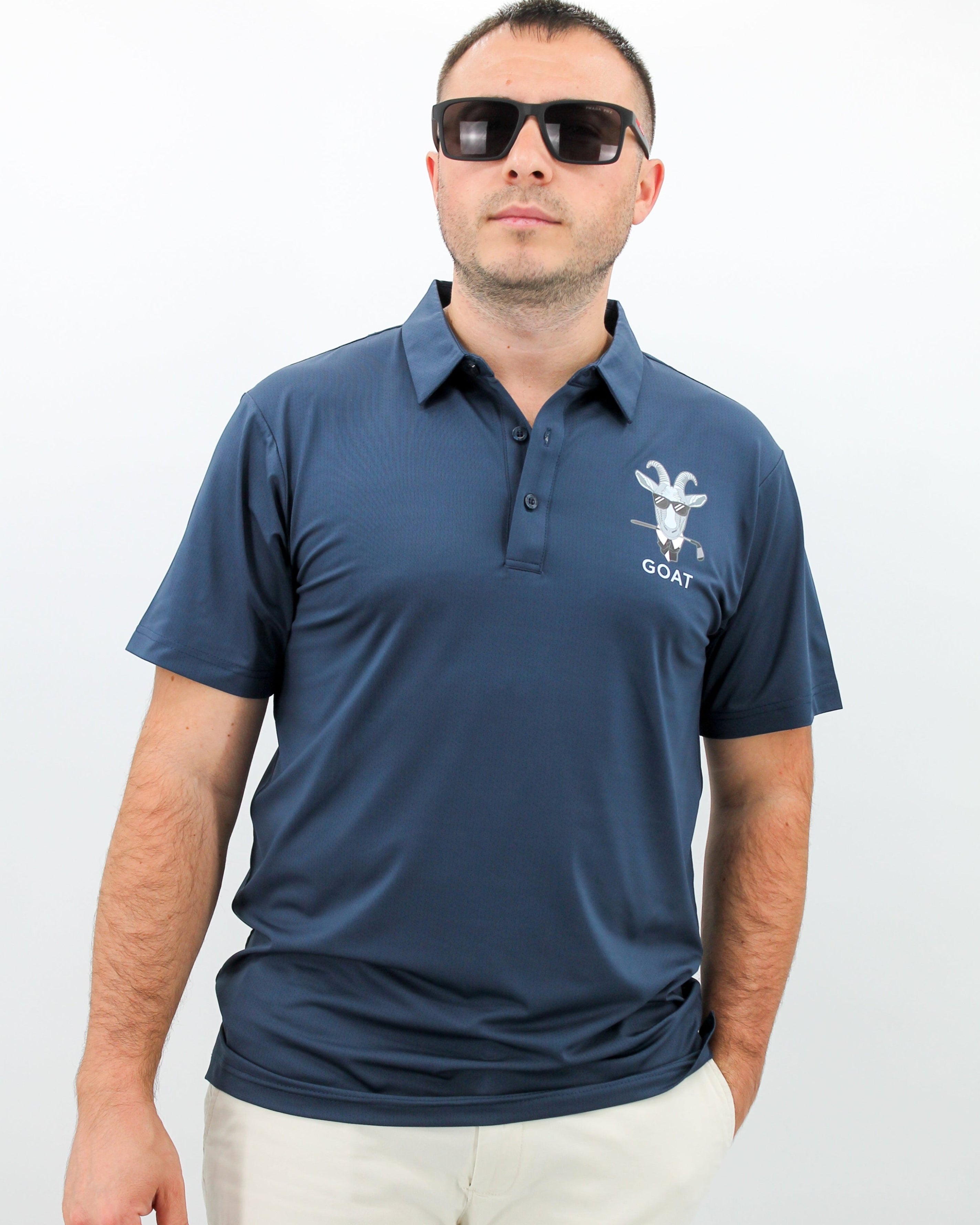 Man wearing a navy blue polo shirt with Goat logo on a white background