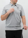 Person wearing a gray polo shirt with a logo on a plain background