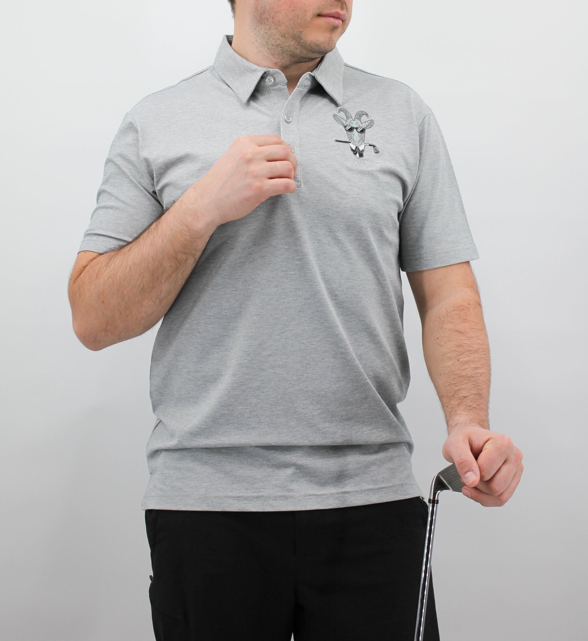 Person wearing a gray polo shirt with a logo on a plain background