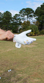 Person holding the 'I'm a simple man' golf glove on a golf course with trees in the background