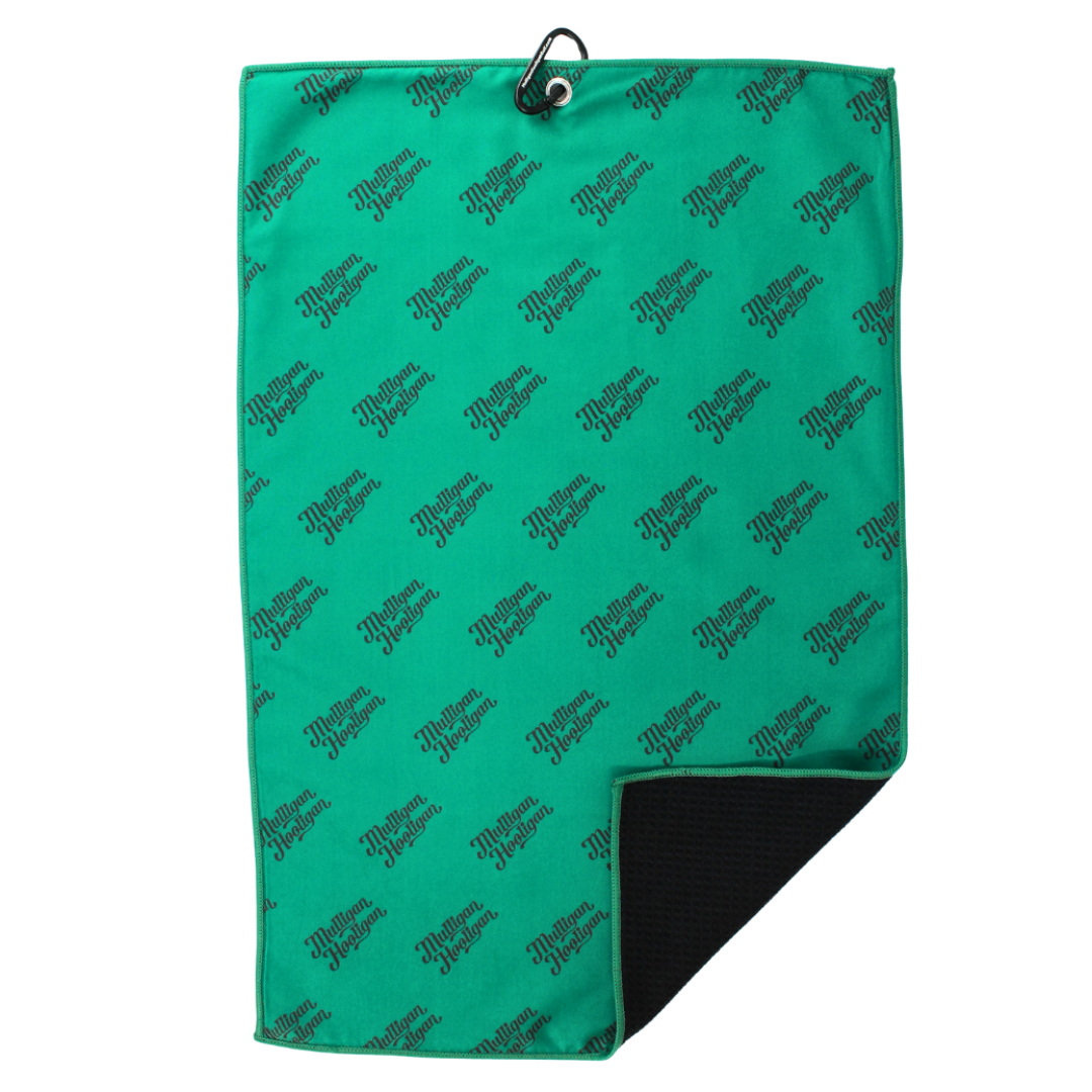 A green golf towel with a repeating black script logo pattern, featuring a black grommet at the top and a folded corner showing a black textured backing, set against a plain white background.