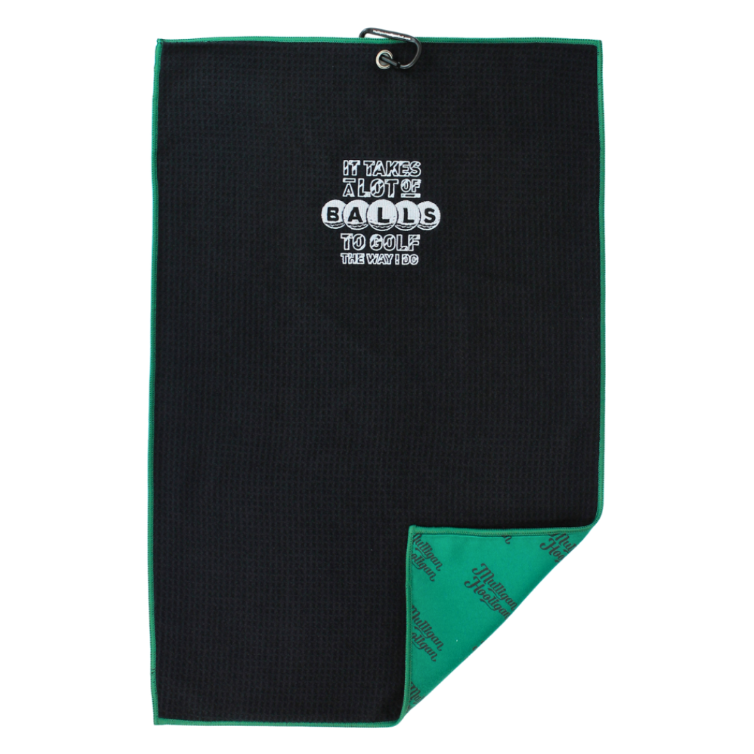 A black golf towel with a green border, featuring a white printed slogan on the front and a green patterned reverse side, shown on a plain white background.
