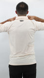 Person wearing a Ecru polo shirt with the brand logo 'Mulligan Hooligan' on the back against a plain background
