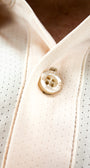 Close-up of a button on a ecru shirt with a blurred background
