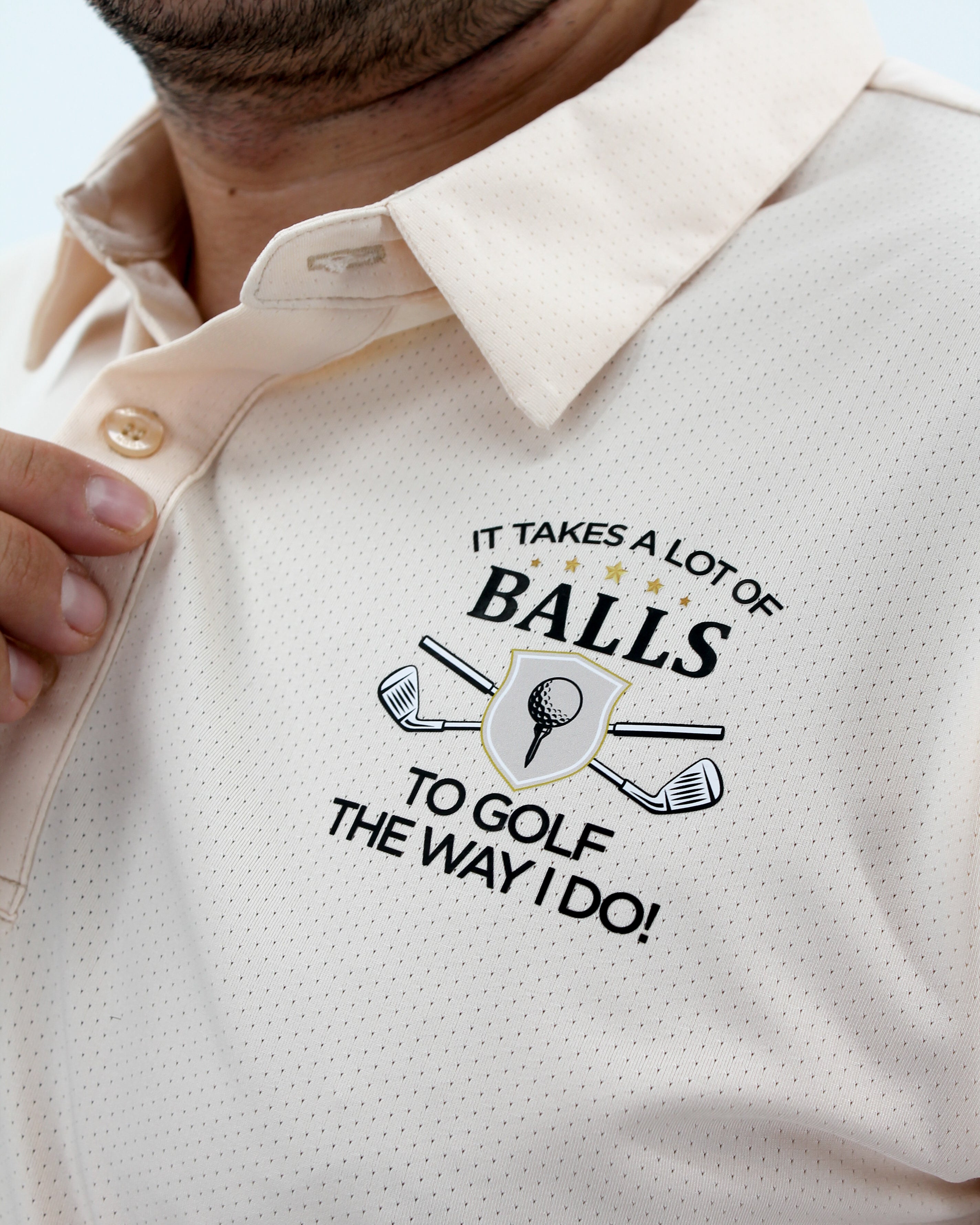 Beige polo shirt with golf-themed text and graphics on a light background