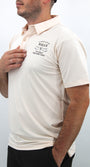 Man wearing a cream-colored polo shirt with text on a plain background