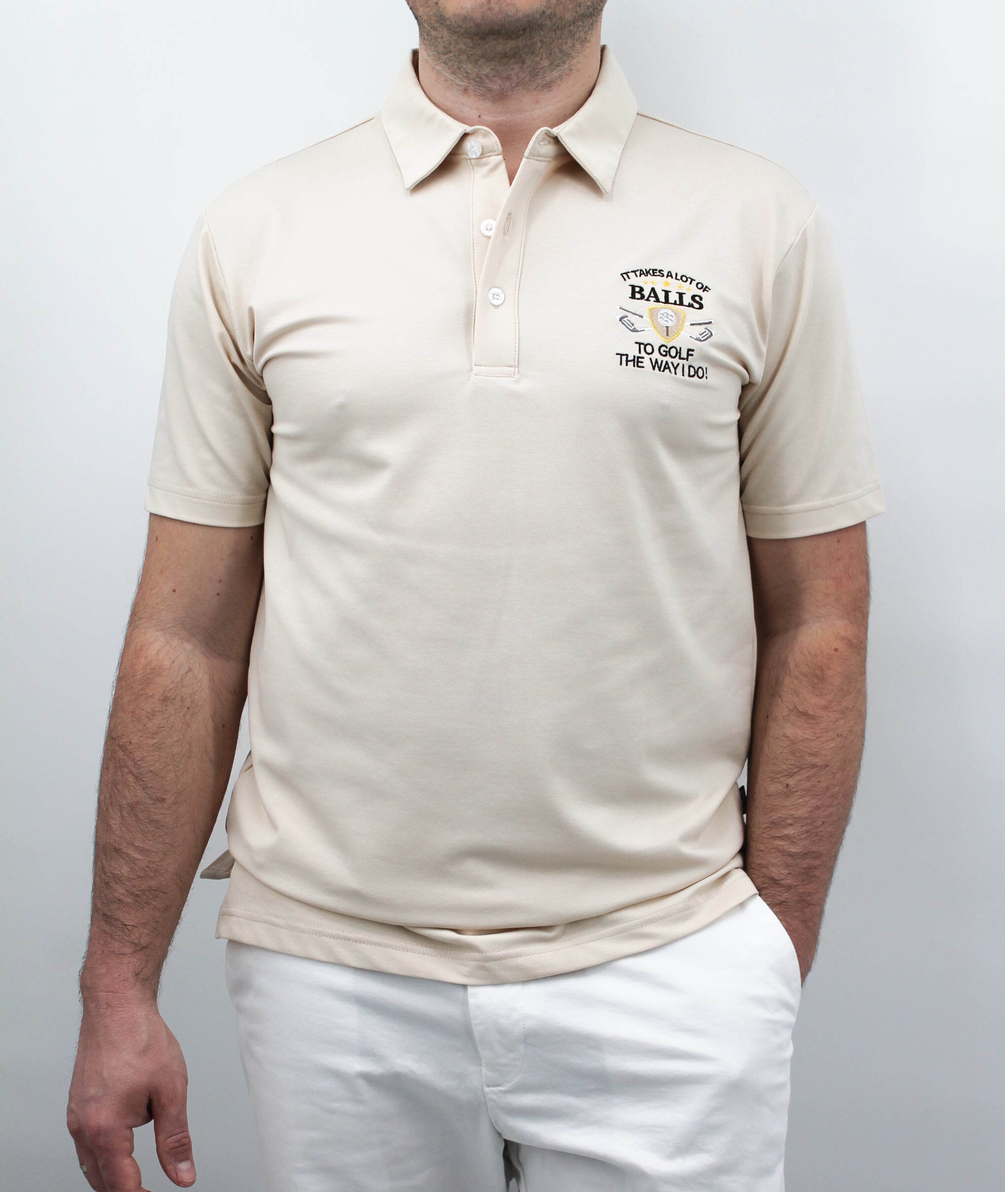 A man wearing a beige polo shirt with the chest artwork: 'It takes a Lot of Balls to play the way I do' with short sleeves, standing against a plain background.