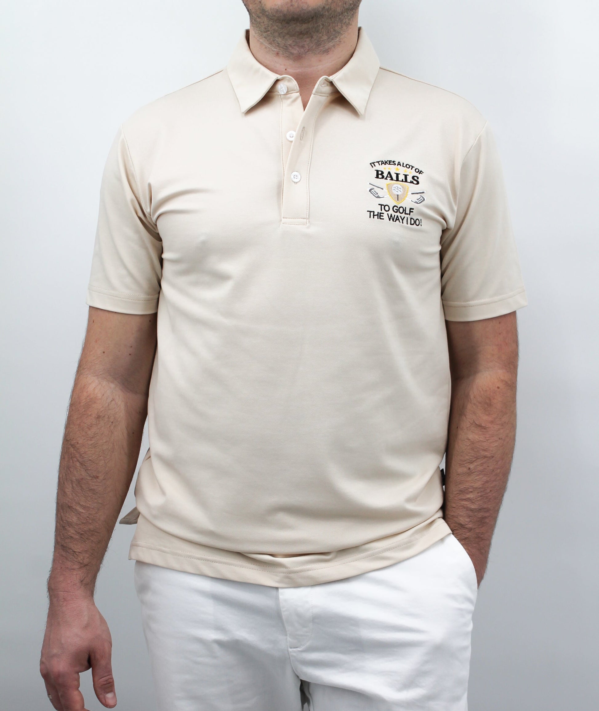 A man wearing a beige polo shirt with the chest artwork: 'It takes a Lot of Balls to play the way I do' with short sleeves, standing against a plain background.