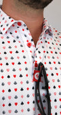 A close-up of a man wearing a white button-down shirt with a repeating playing cards pattern of red, black, and gray playing card suits.