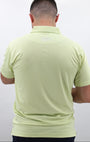 Man wearing a light pistachio polo shirt with a brand logo 'Mulligan Hooligan' on the back against a white background