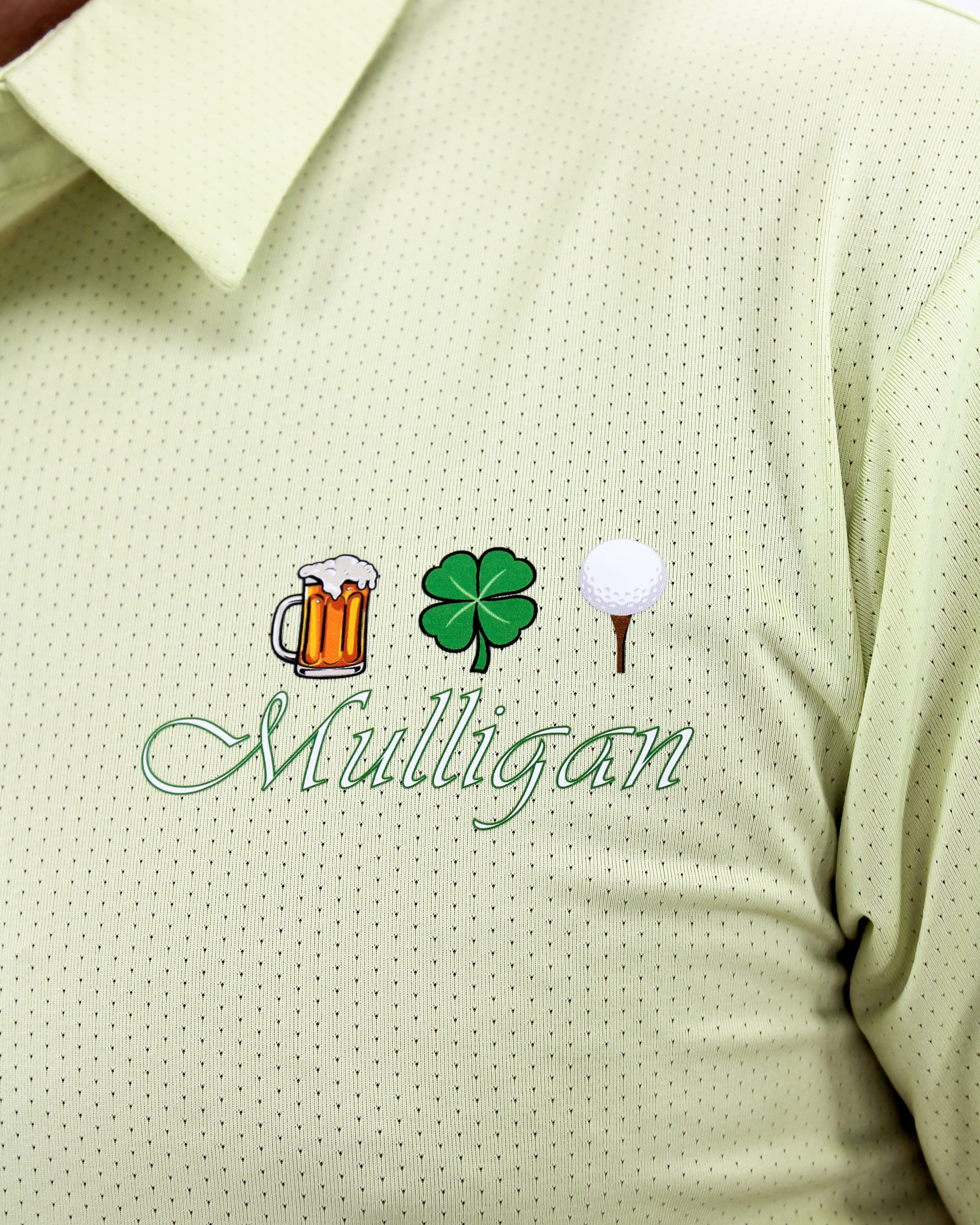Light green polo shirt with 'Mulligan' design featuring a beer mug, clover, and golf ball on a white background.