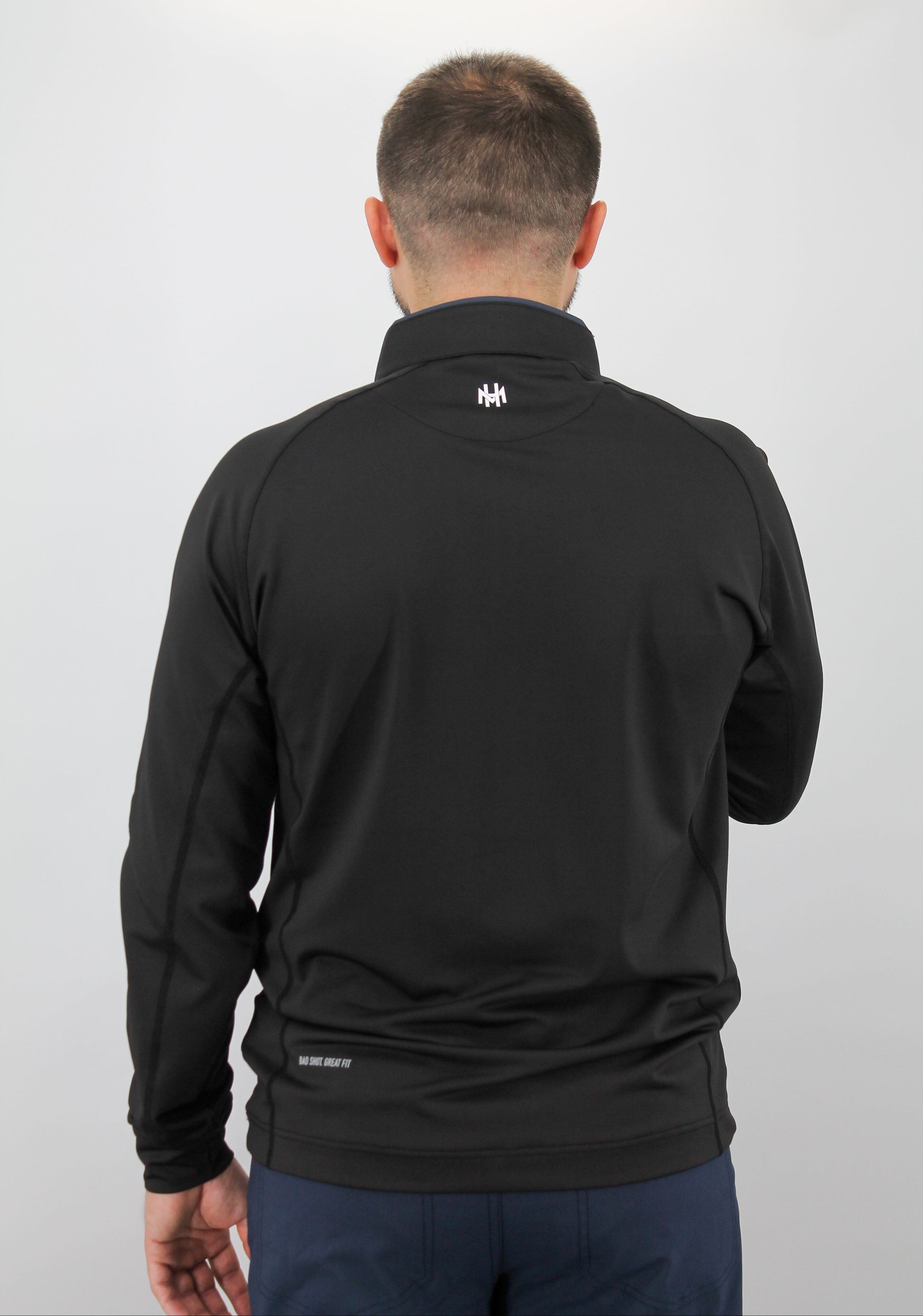 Person wearing a black jacket with a logo on the back against a white background