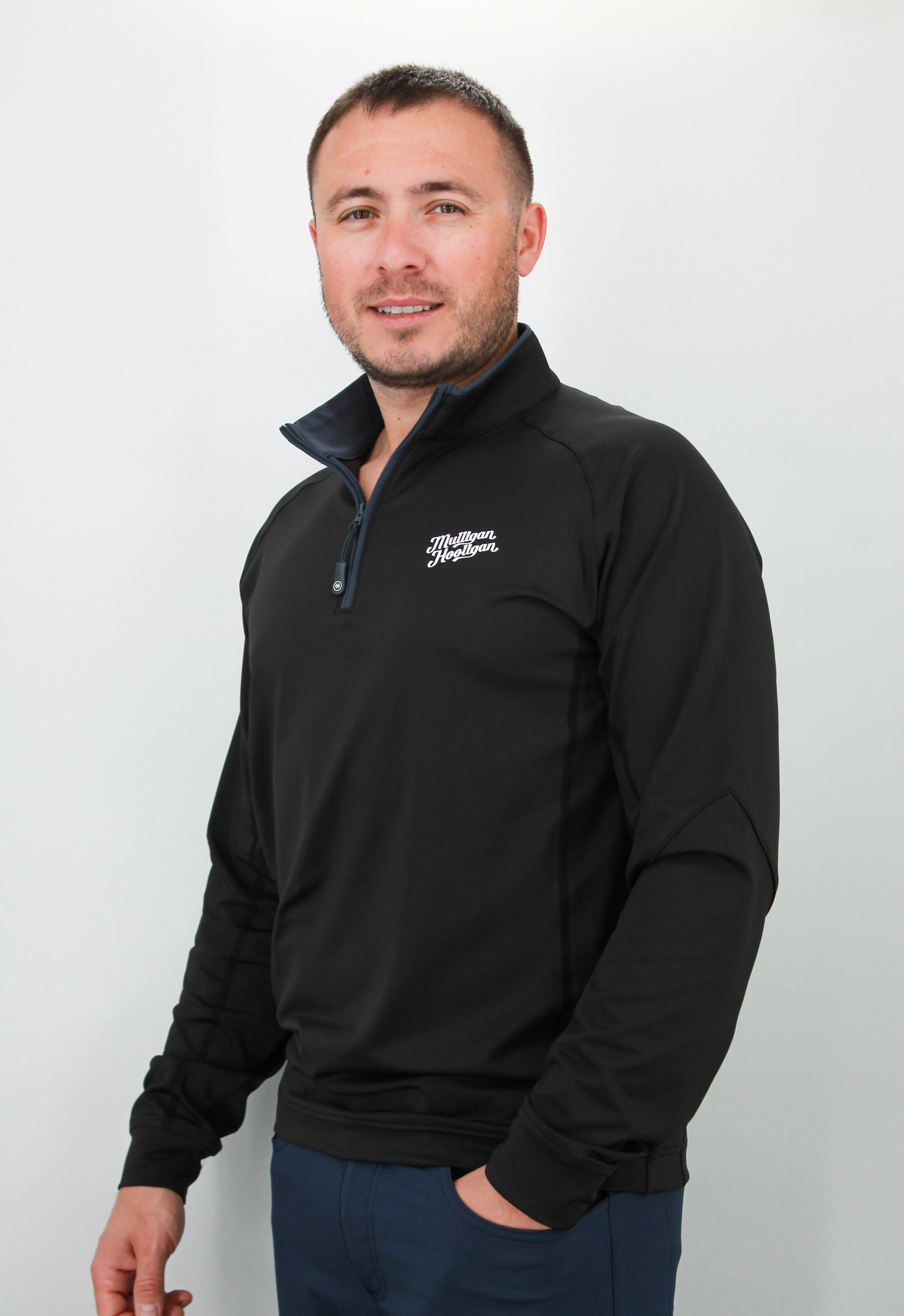 Man wearing a black quarter zip with a logo on a white background