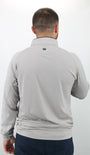 Man wearing a gray long-sleeve shirt with a brand logo on the back against a white background
