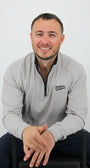 Man wearing a gray sweatshirt with a logo, sitting on a white background