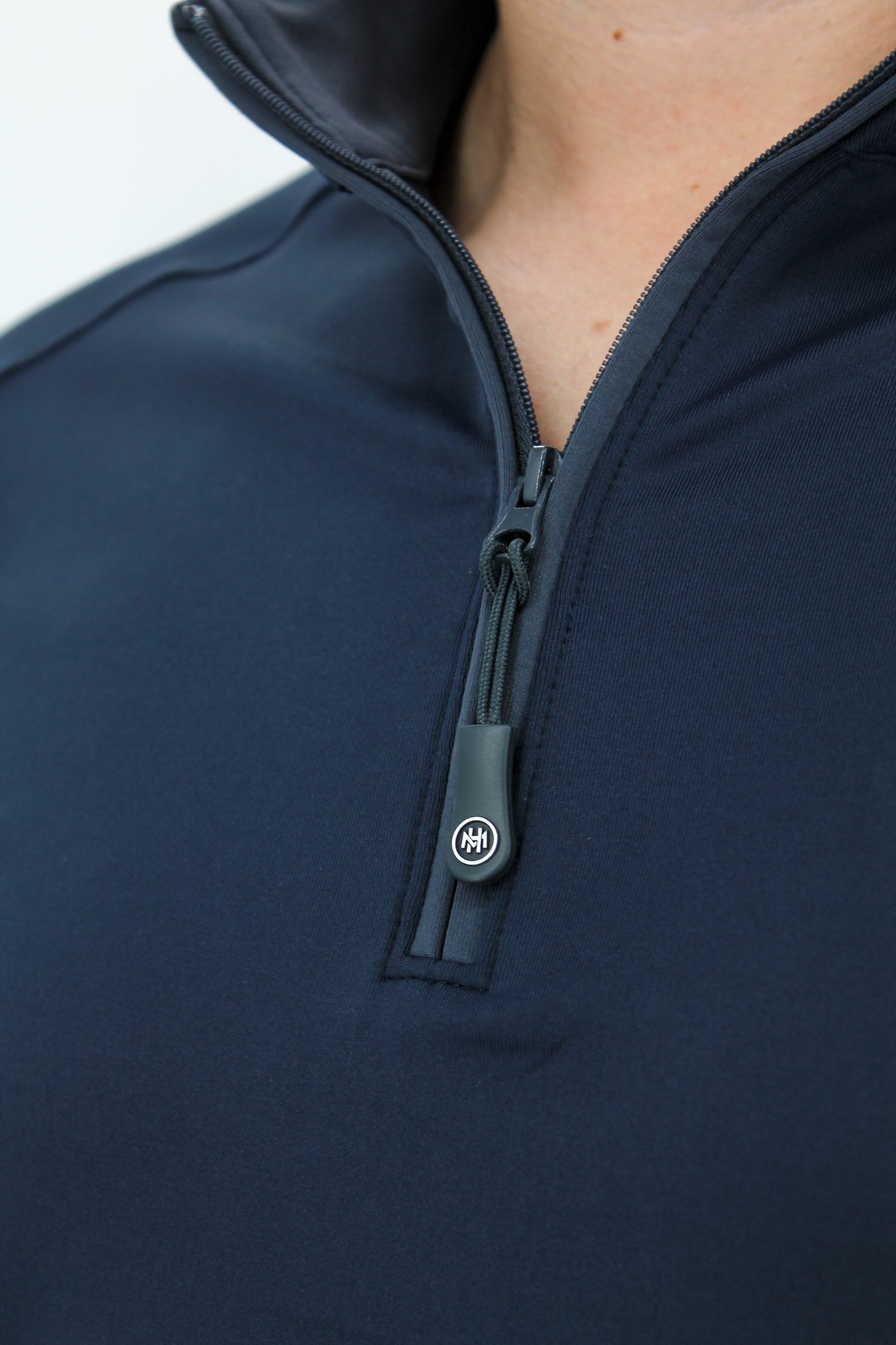 Close-up of a navy blue zip-up garment with a brand logo on the zipper.