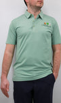 A man wearing a green polo shirt with a logo on the chest. The polo shirt has short sleeves and a collar.