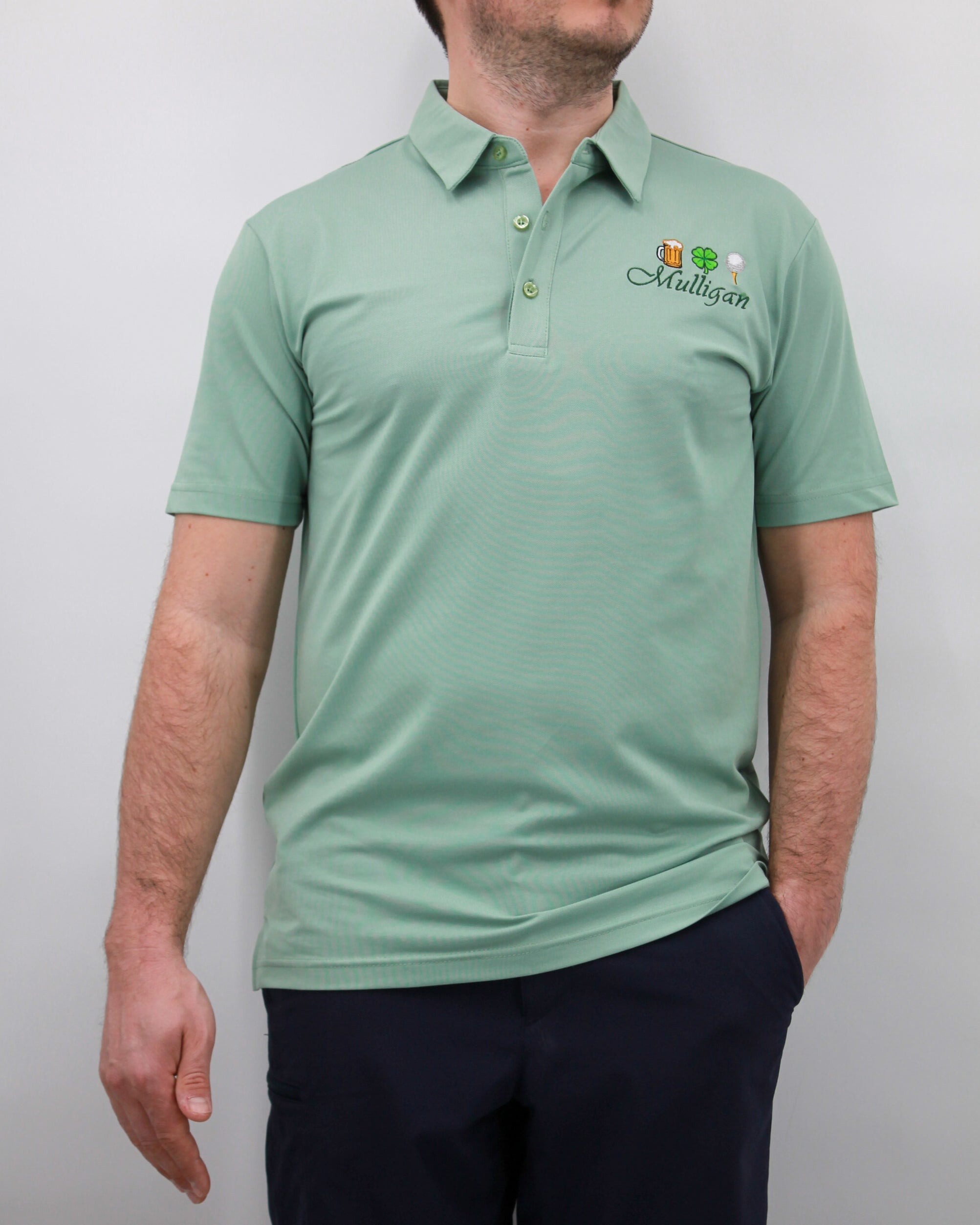 A man wearing a green polo shirt with a logo on the chest. The polo shirt has short sleeves and a collar.