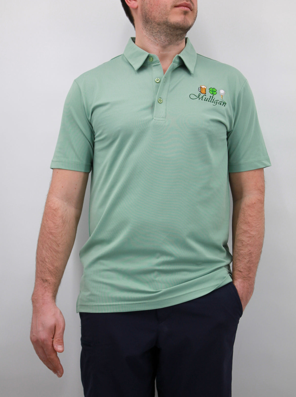 A man wearing a green polo shirt with a logo on the chest. The polo shirt has short sleeves and a collar.