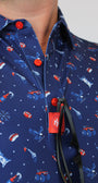 Close-up of a navy blue shirt with a patriotic red, white, and blue pattern of sports figures, stars, and flags, featuring red snap buttons and a red 'MH' brand tag.