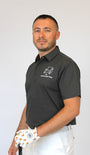 A man wearing a dark gray short-sleeve polo shirt with a white golf club and white pants, holding the club with a white golf glove. The polo shirt features a white logo on the left chest that reads 'My Retirement Plan'.