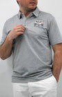 A man wearing a gray polo shirt with a graphic design in the center, standing against a white background.