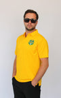 A man wearing a bright yellow short-sleeve polo shirt with a green and white 'Okayest Golfer' Graphic Golf Polo crest on the left chest, paired with black shorts and sunglasses, standing against a plain white background.