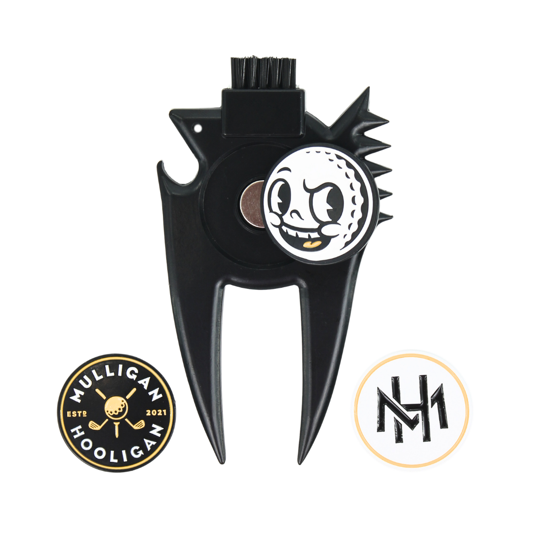 A black metal golf divot tool with a skull-and-golf-ball emblem in the center, shown on a plain white background with two circular brand logos below it.