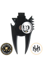 A black metal golf divot tool with a skull-and-golf-ball emblem in the center, shown on a plain white background with two circular brand logos below it.
