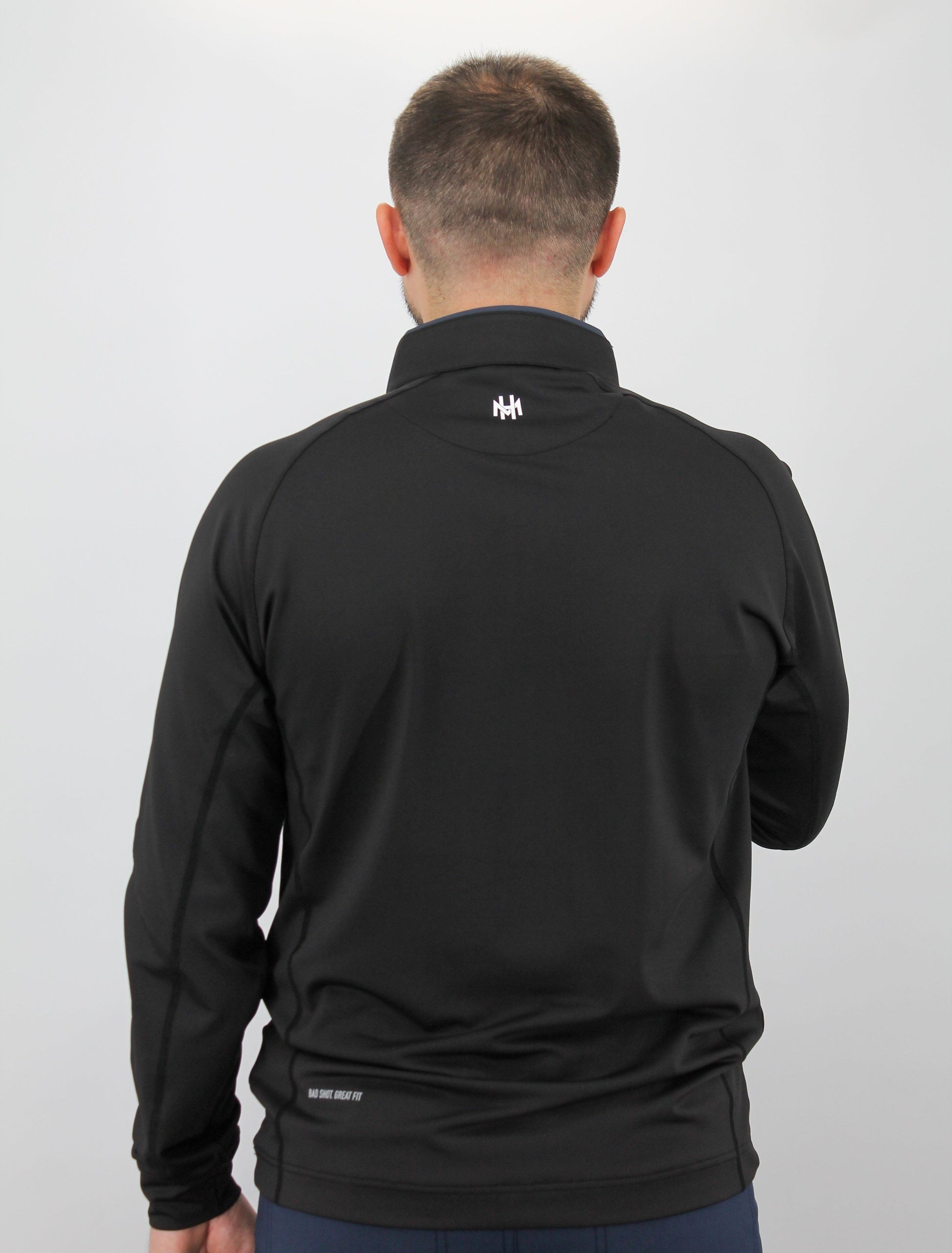 Person wearing a black jacket with a logo on the back against a white background