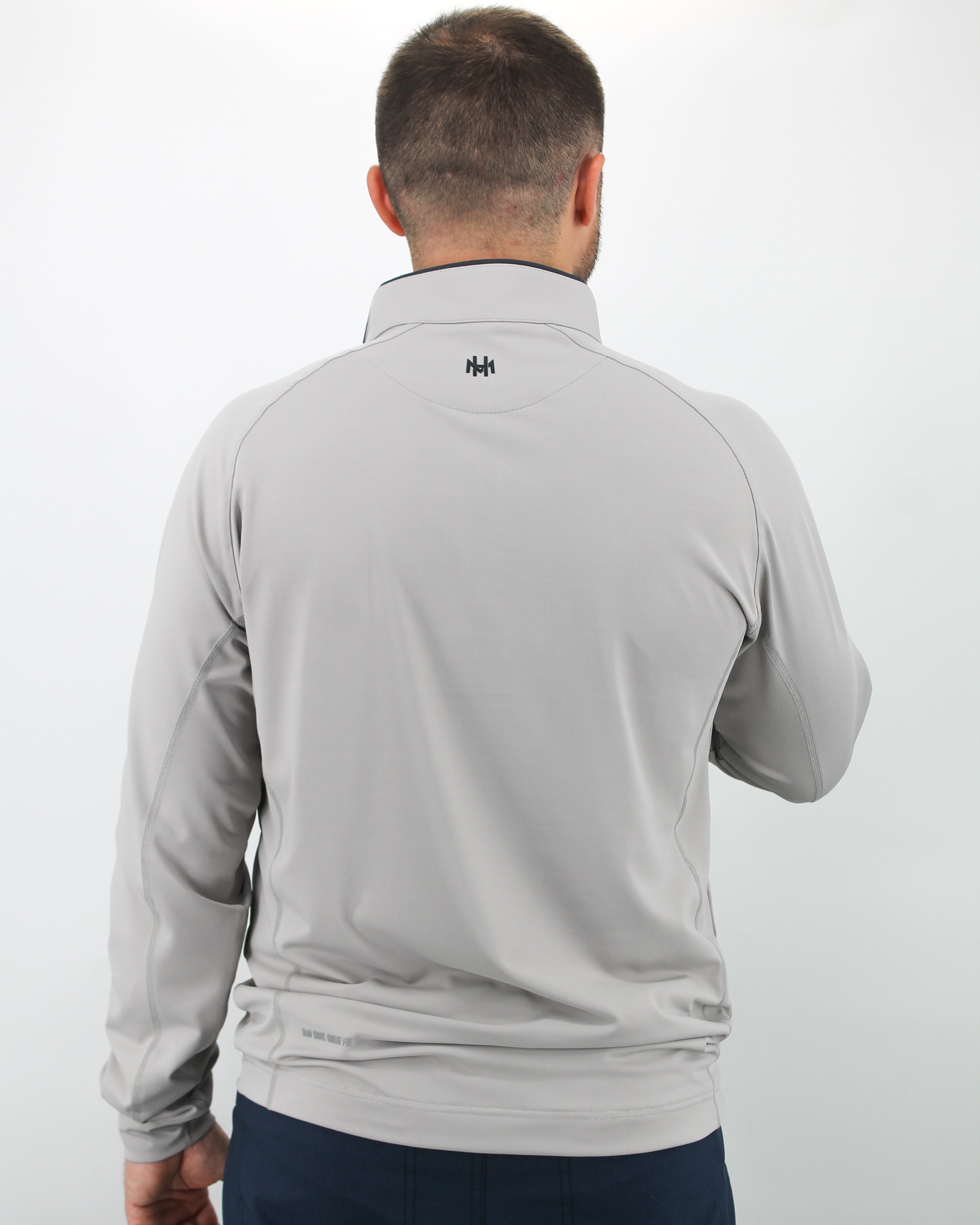 Man wearing a gray long-sleeve shirt with a brand logo on the back against a white background