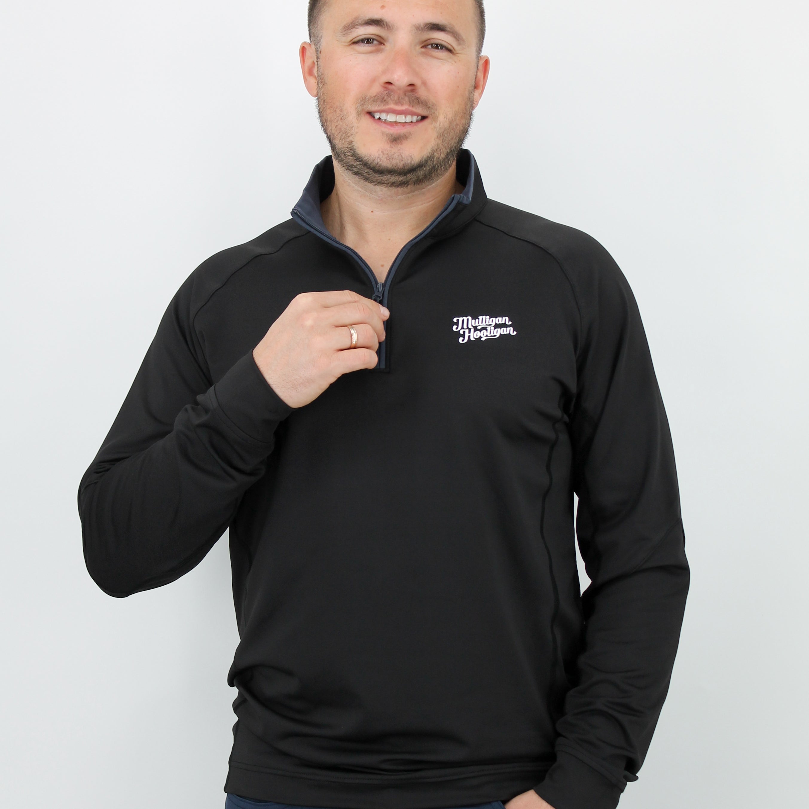 Man wearing a black pullover with 'Mulligan Hooligan' logo on left chest on a white background